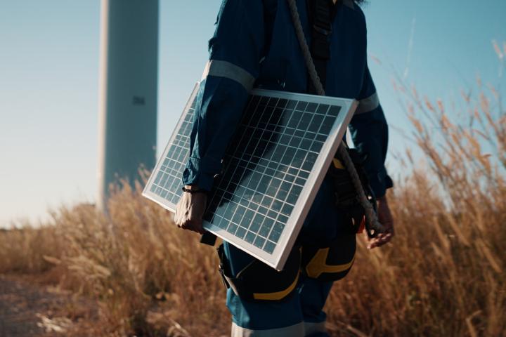 Imagen de archivo de una persona llevando una placa solar bajo el brazo.