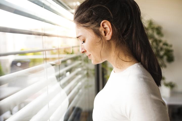 Imagen de archivo de una mujer angustiada junto a la ventana.