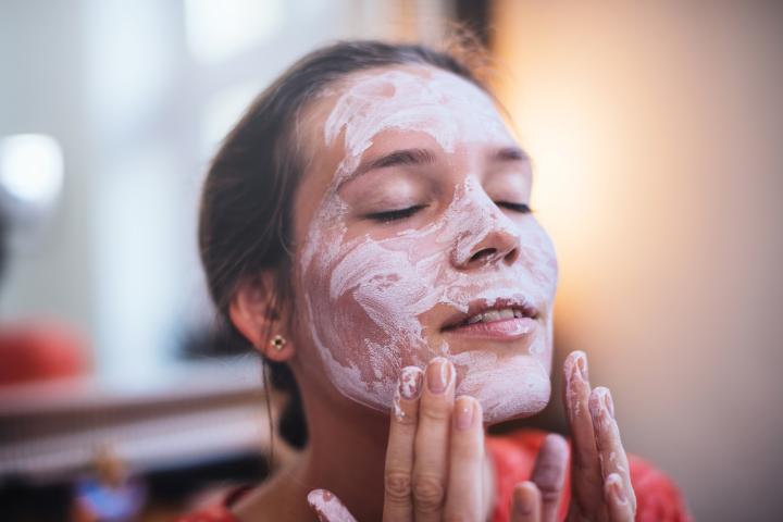 Una mujer aplicándose una mascarilla facial.