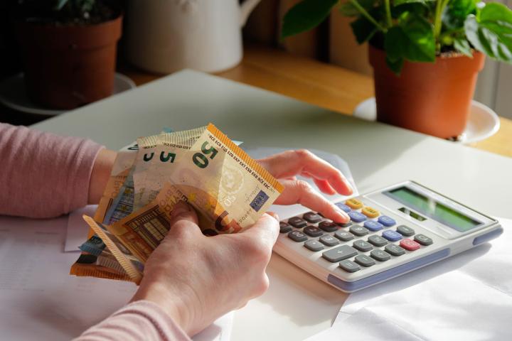 Una mujer echando cuentas con billetes en la mano.