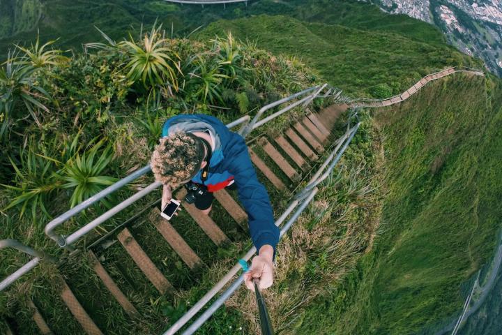 Un joven asciende mirando el móvil por las Escaleras Haiku, en la isla de Oahu, Hawái.