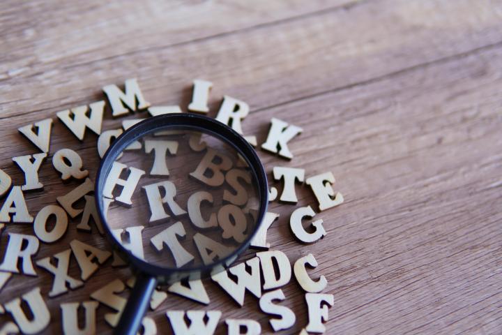 Lupa con letras del alfabeto esparcidas sobre la mesa