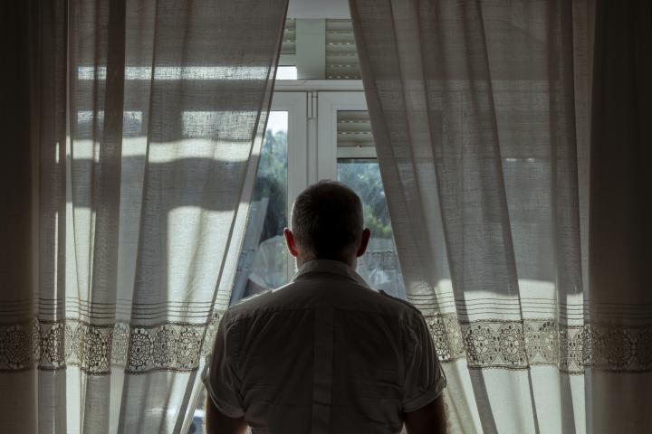 Imagen de archivo de una persona mayor viendo algo por la ventana.