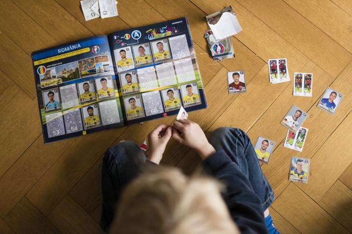Un niño completando una colección de cromos de fútbol.