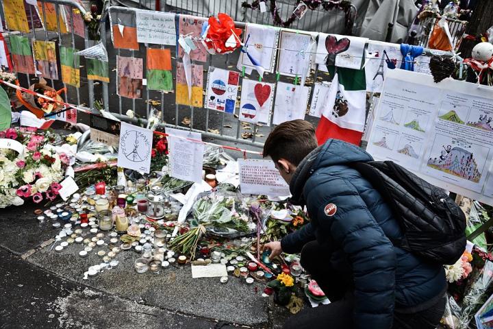 Un joven deposita flores en homenaje a los atentados de París de 2015.