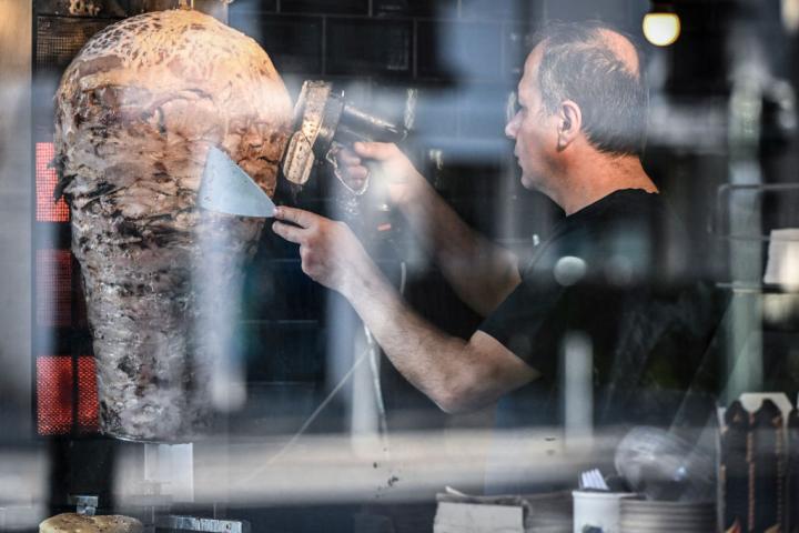 Un restaurador turco de Berlín corta la carne que utilizará en la elaboración de un kebab.