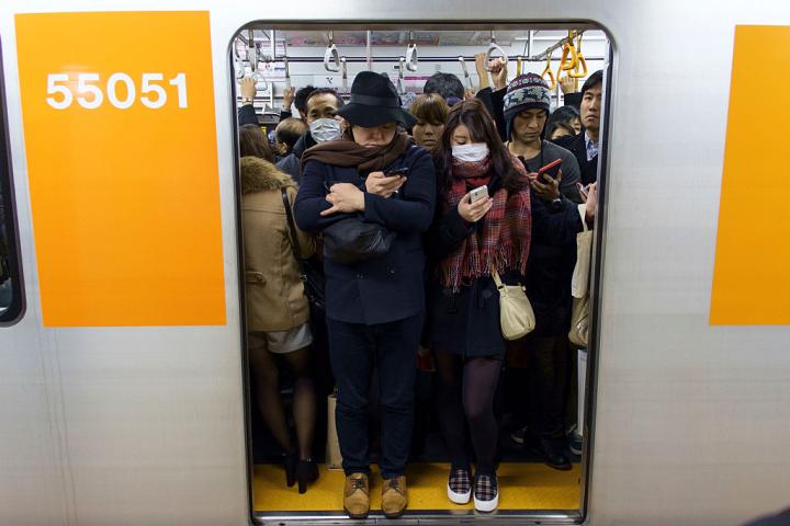Trabajadores japoneses esperan en una estación de metro de Tokio a que arranque el tren.
