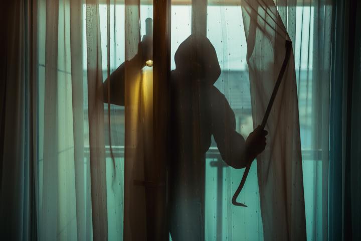 Imagen de una persona encapuchada entrando en una vivienda.