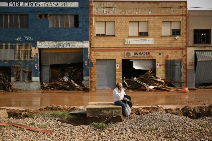 Un hombre habla por teléfono en una calle inundada tras el paso de la DANA por Valencia.