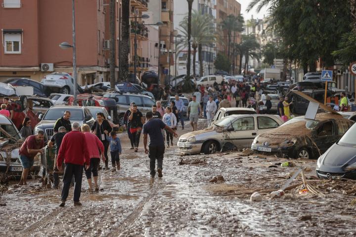 Varias personas caminan por una de las calles afectadas en Paiporta, tras las fuertes lluvias causadas por la DANA.