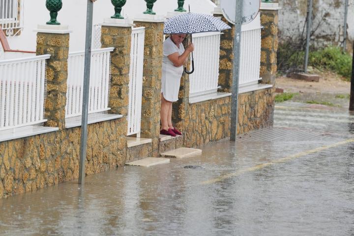 Una persona intenta cruzar una calle inundada en la barriada Bazán de San Fernando (Cádiz).