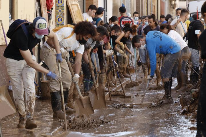 Varias personas retiran el lodo acumulado en una calle de la localidad valenciana de Paiporta, este sábado.
