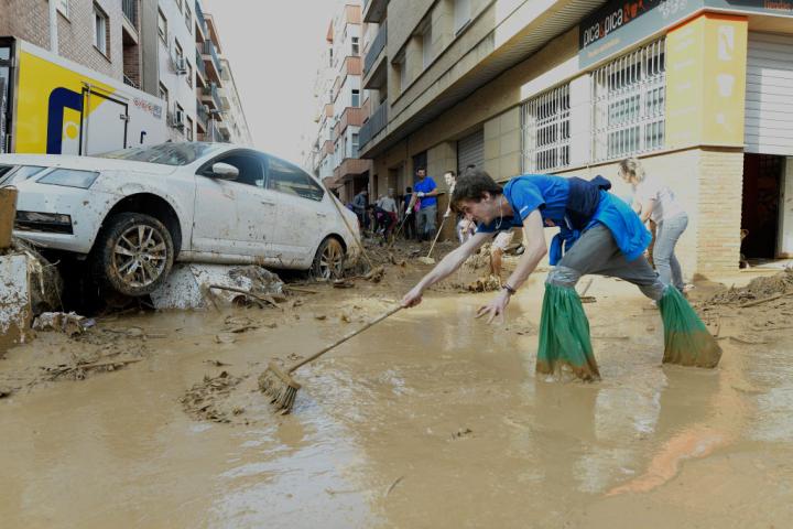 Una voluntaria limpia el barro en las calles de Paiporta.