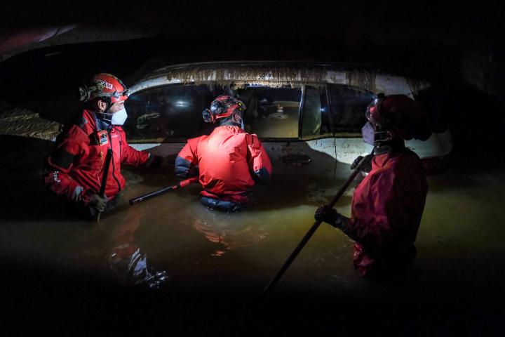 Bomberos inspeccionan un vehículo con el agua por la cintura