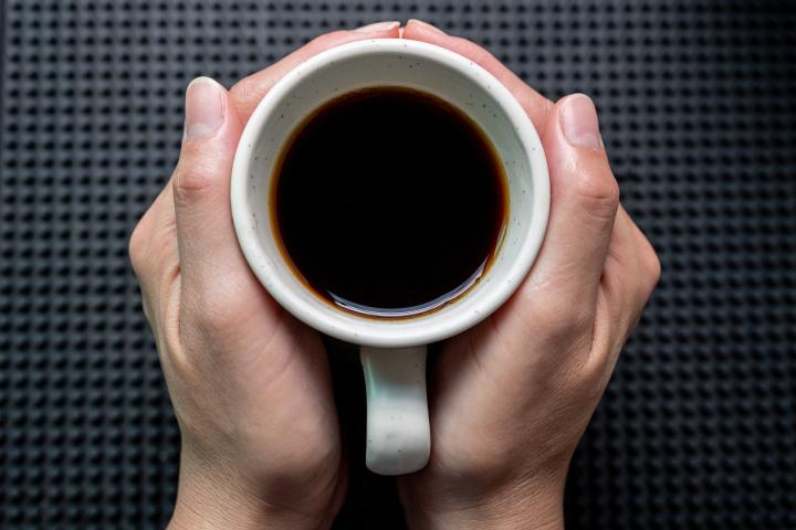 Una persona con una taza de café entre las manos.