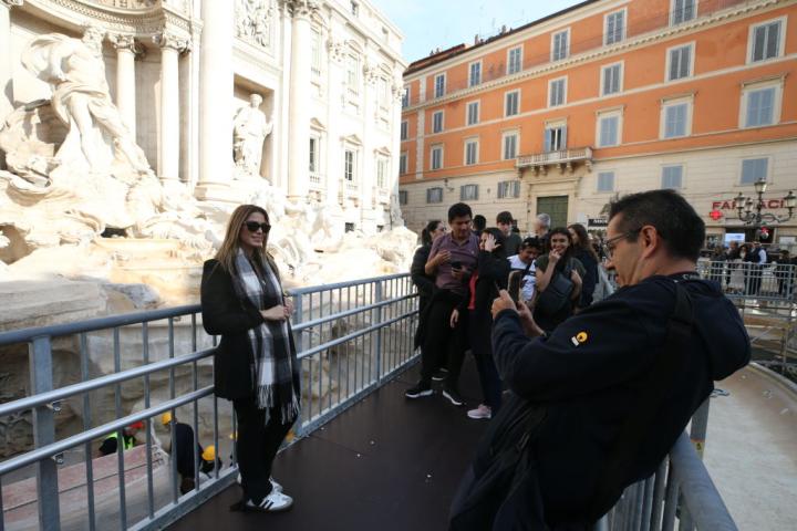 Un grupo de turistas se fotografía desde la nueva pasarela instalada en la Fontana di Trevi.