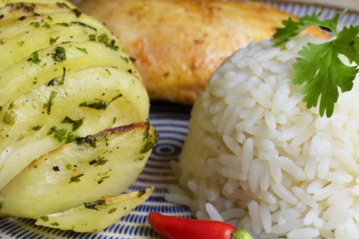 Una patata aderezada y arroz en un plato, listo para consumir.
