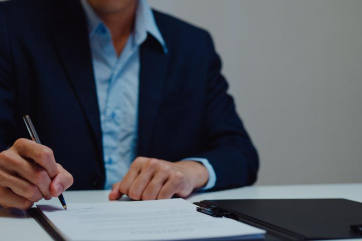 Un hombre firmando unos papeles.