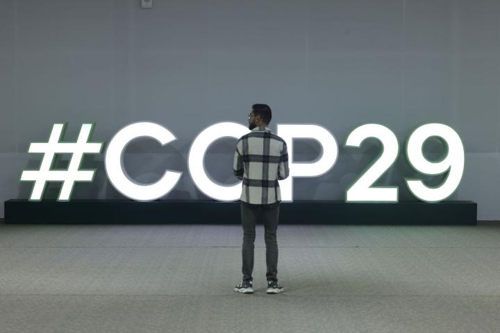 Un asistente a la COP29 de Bakú, ante una señal luminosa de la cumbre climática.