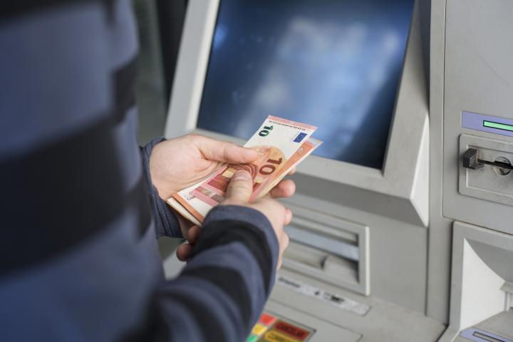 Una persona retira dinero en efectivo de un cajero automático.