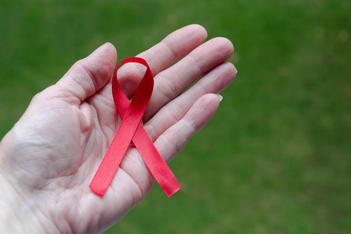 Mujer sosteniendo un lazo rojo de sensibilización frente al sida.