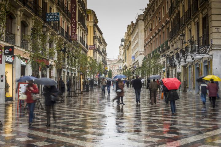 Transeúntes caminan bajo la lluvia en la Calle Arenal de Madrid.
