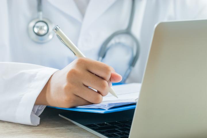 Una médico firma un certificado.