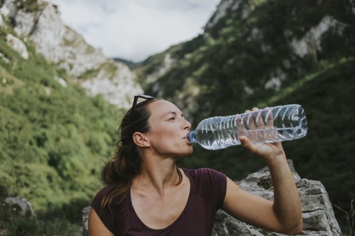 Una mujer bebiendo agua embotellada.