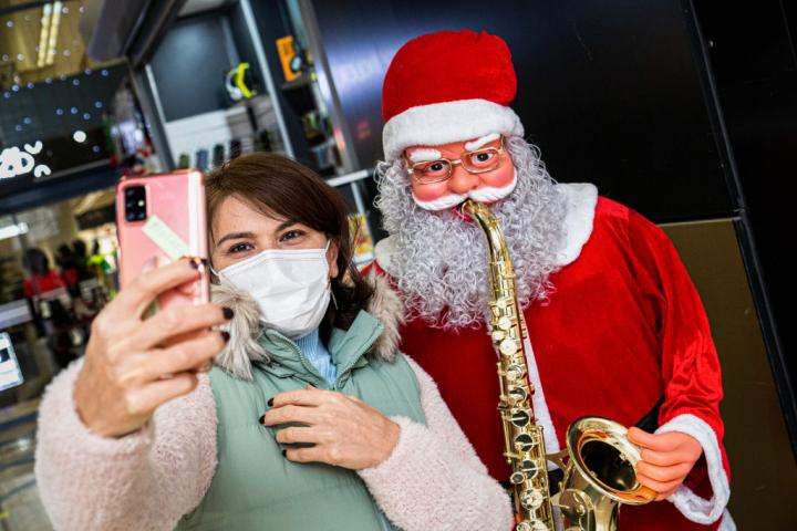 Una mujer que lleva una mascarilla se toma un selfie con un maniquí de Papá Noel.