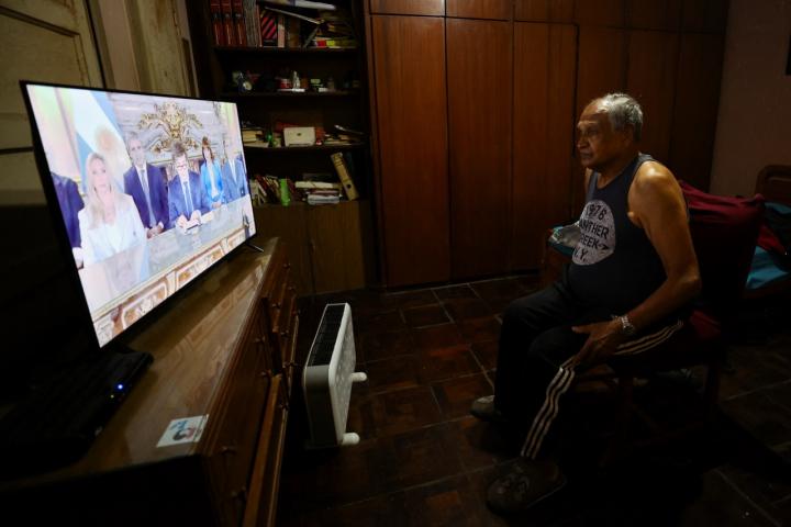 Un jubilado ve el discurso televisado del primer aniversario del Gobierno de Javier Milei.