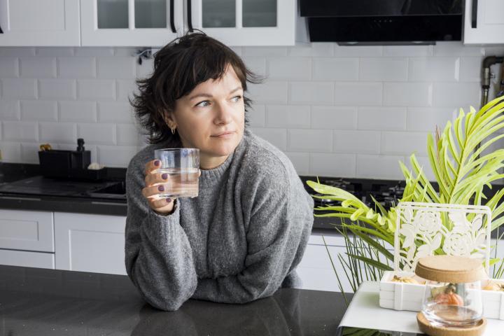 Una mujer bebiendo un vaso de agua.
