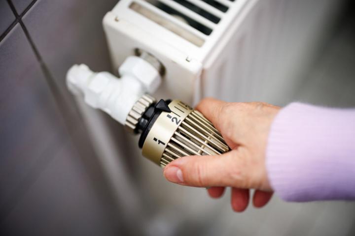 Una mujer sube la temperatura de un radiador conectado a una calefacción de gas.