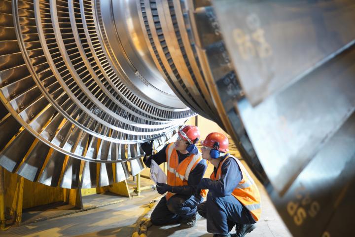 Unos mecánicos arreglan una turbina.