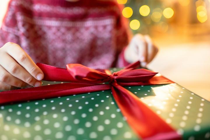 Una persona abre un regalo en una imagen de archivo.