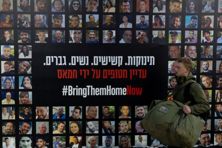 Un soldado pasa junto a un muro cubierto de fotos de rehenes israelíes retenidos por Hamás