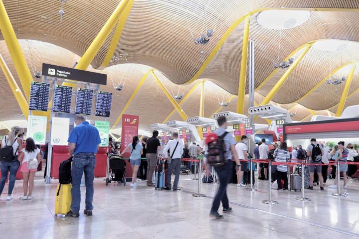 Viajeros hacen cola en un mostrador de facturación del aeropuerto de Madrid.