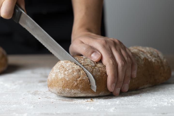 Imagen de archivo de una mujer cortando pan.