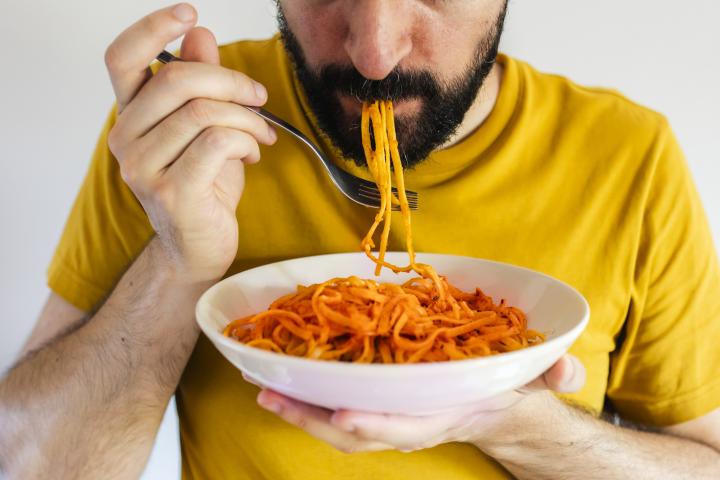 Un hombre comiendo un plato de pasta.