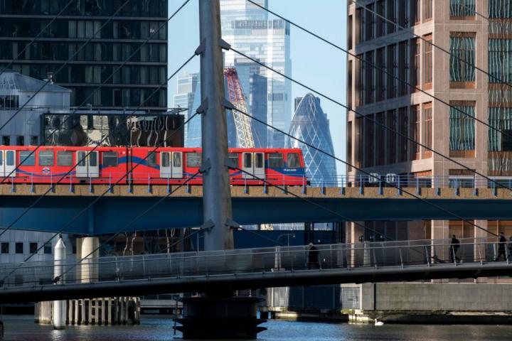 Uno de los trenes de la red DLR de Londres con los rascacielos de la City de fondo.