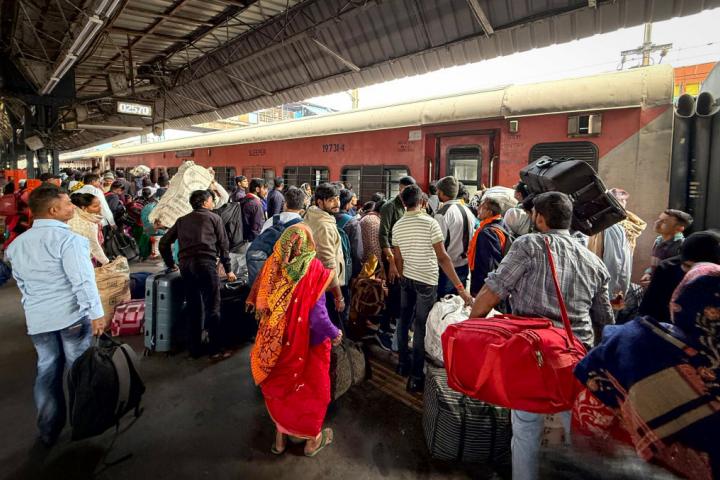 Un grupo de pasajeros intenta subirse a un tren en la estación de Nueva Delhi.