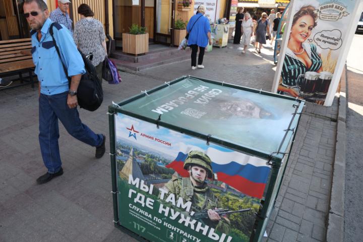 Un hombre pasa frente a un cartel de propaganda militar colocado en en las calles de Moscú con la imagen de un oficial de las Fuerzas Armadas rusas