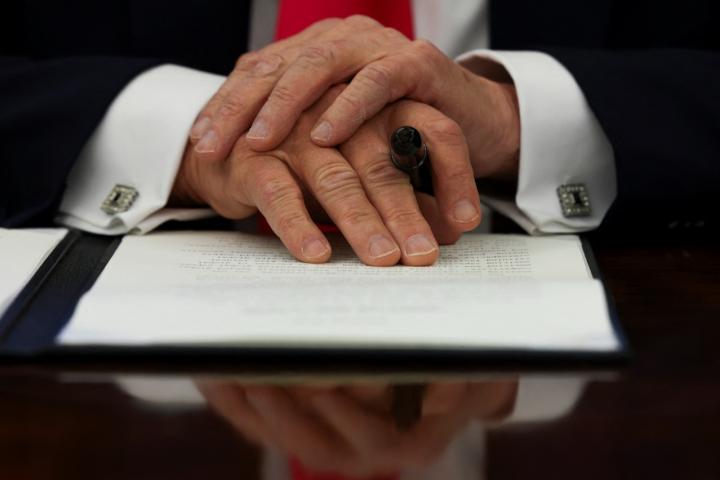 El presidente de Estados Unidos, Donald Trump, cruza sus manos sobre el decreto que acaba de firmar.