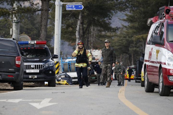 El personal de los servicios de rescate y los soldados caminan cerca del lugar del bombardeo accidental de un avión de combate, en Pocheon, Corea del Sur.