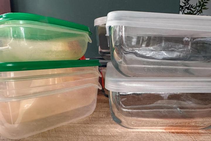 Tuppers de plástico y de cristal encima de una mesa de madera.