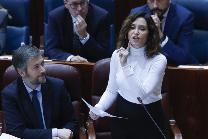 La presidenta de la comunidad de Madrid, Isabel Díaz Ayuso (d), y el consejero de Presidencia, Justicia y Administración Local, Miguel Ángel García Martín, durante la sesión de control celebrada en el pleno de la Asamblea de Madrid este jueves. El quinto aniversario del inicio de la pandemia del coronavirus y las cifras de los muertos en las residencias de mayores son el tema central de este pleno.