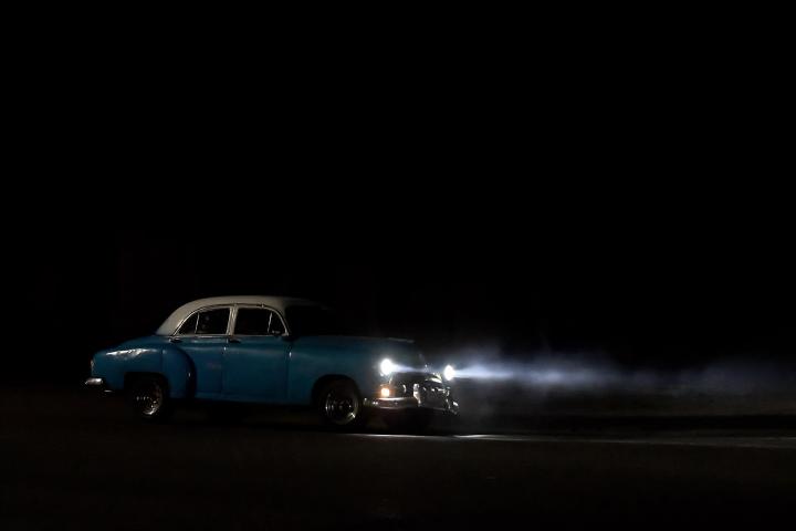 Un coche conduce a la luz de la noche en Cuba.