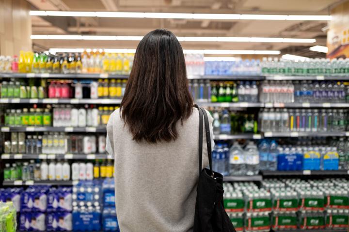 Una chica en el lineal de bebidas del supermercado.