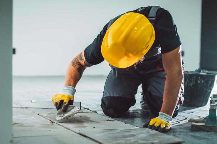 Imagen de un obrero alicatando baldosas.