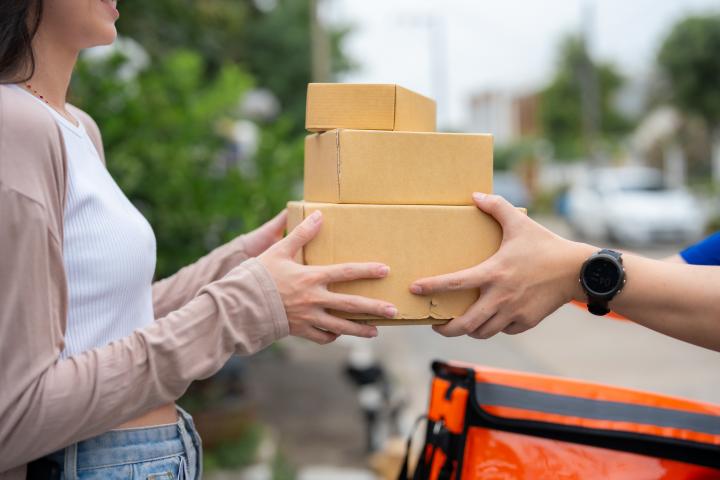 Imagen de una mujer recibiendo paquetes de un mensajero.