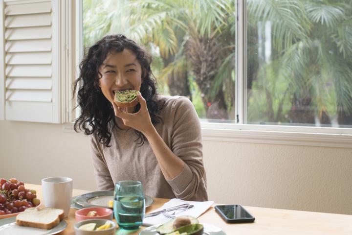Una mujer comiendo unas tostada de aguacate.